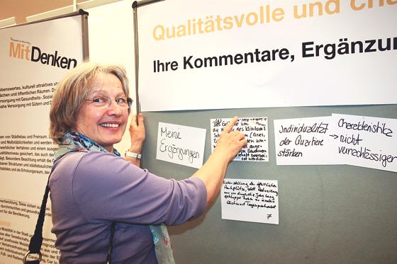 Eine Bürgerin pickt den Zettel mit ihren Wünschen für den Münchner Norden an die Stellwand im Kulturhaus Milbertshofen. 	Foto: ws