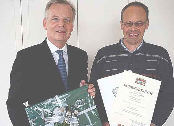 Wolfgang Reger (rechts) wurde für sein 25. Dienstjubiläum von Bürgermeister Jan Neusiedel (links) eine Ehrenurkunde überreicht. 	Foto: Gemeinde Grünwald