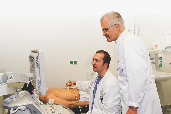 Dr. Thomas Nicolaus und Dr. Peter Kreissl (v. li.) untersuchen einen Patienten mit  Oberbauchschmerzen.	Foto: kk