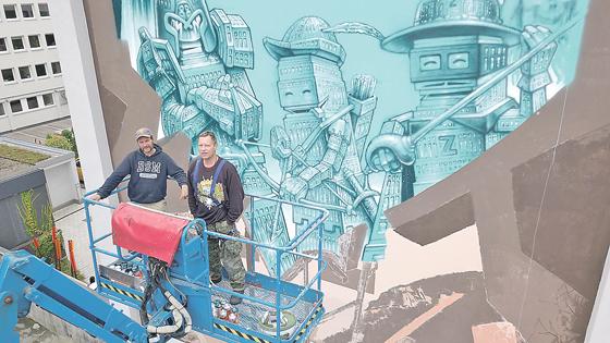 Die beiden Künstler Loomit und WON ABC vor einem Ausschnitt ihres noch nicht vollendeten Streetart-Werks zu Ehren von Georg Elser.	Foto: Frank Prekratic