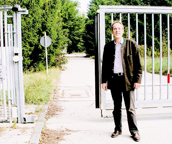 Bürgermeister Dr. Stefan Straßmair öffnet schon einmal probeweise das Tor zum geplanten Gewerbegebiet in der Muna.  Foto: Schwarz-Mehrens