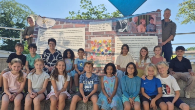 Spaß mit Banner (1. Reihe v.l.): Franziska, Clara, Karla, Anton, Kaya, Mara, Simon und Tom, (2. Reihe v.l.) Bene, Ben Luca, Brigitte Kössinger, Zoë, Vicenzo, Milana, Karlotta, Josefine und Muhammed sowie (dahinter mit Banner) Klassenlehrerin Isabella Roman und Rathausmitarbeiter Sebastian Hofmüller. (Foto: Gemeinde Gauting)