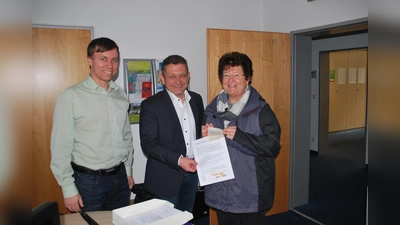 Bürgermeister Korneder begrüßte gemeinsam mit Sebastian Stüwe vom Umweltamt erste Bürgerin, Annemarie Weinberger, die sich das Saatgut im Rathaus abholte. (Foto: privat)