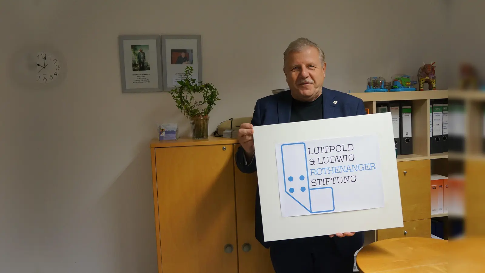 Zum Geburtstag der Rothenanger-Stiftung gab es ein Logo, das mittels eines Wettbewerbs ausgelobt wurde. Das Siegerlogo, ein Pflaster, stammt aus der Feder von Bennet Deboben aus Riemerling. Hier wird es präsentiert vom Stiftungs-Vorsitzenden Albert Oehrlein. (Foto: hw)