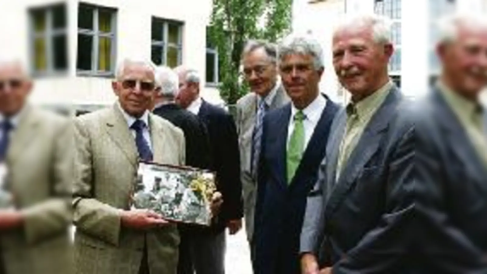 Dort wo sie Handball gespielt haben, im Hof des Gisela-Gymnasiums, überreichte der Abiturjahrgang 1957 seinem Klassenlehrer Heribert Moser (2.v.li.) ein Foto vom gemeinsamen dreitägigen Radlausflug nach Rottenbuch.  (Foto: ms)