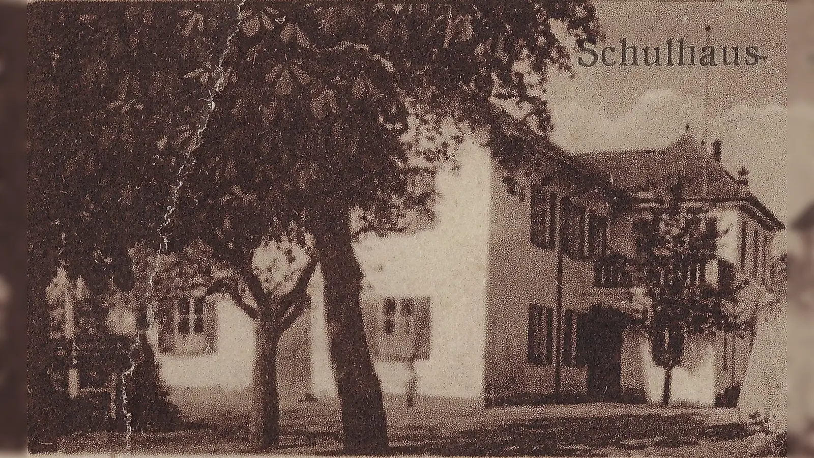 Das alte Schulhaus Taufkirchens hinter der Kirche St. Johannes um 1930.  (Foto: Gemeindearchiv)