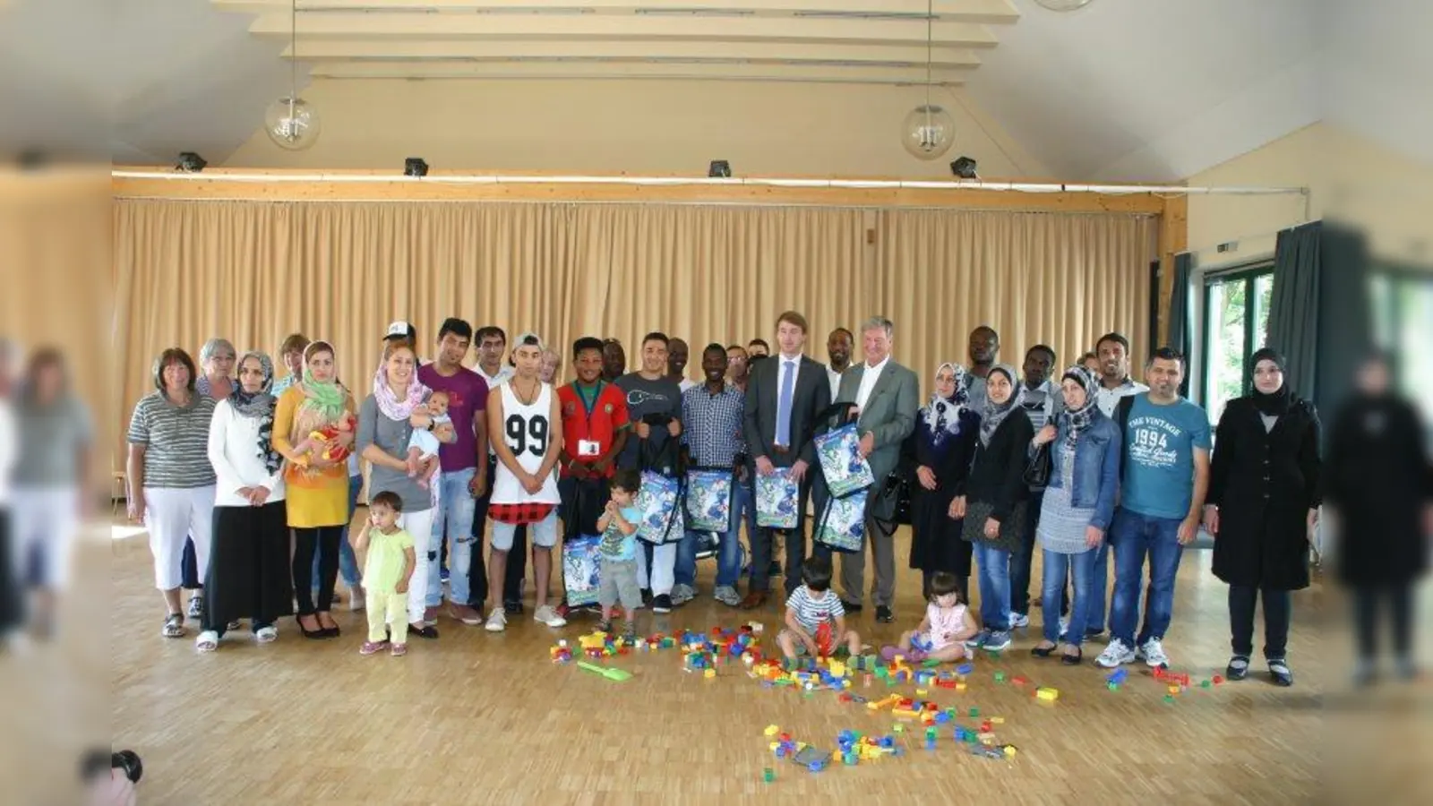 Andreas Buchner, Abteilungsleiter im Ausländeramt und Frederik Röder, Bürgermeister der Gemeinde Alling mit Asylbewerbern bei der Übergabe der Informationstaschen. (Foto: pst)