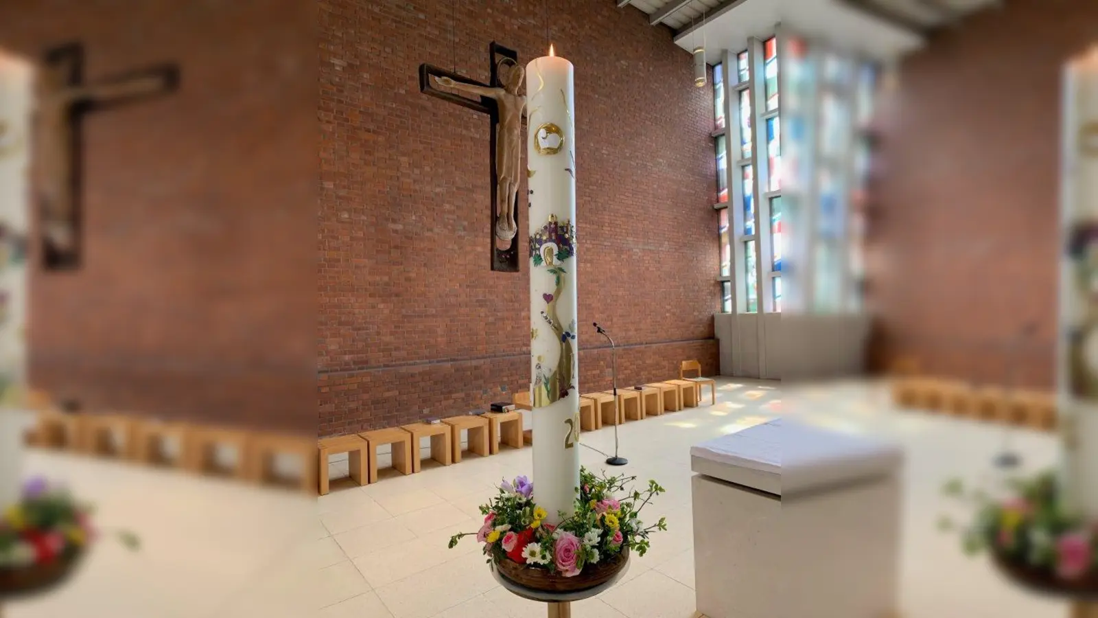 Brennende Osterkerze in der Pfarrkirche St. Johannes Bosco, von Dr. Christine Moritz-Brokamp aufwändig gestaltet, perspektivisch vor dem großen Kreuz über dem Altar. „Tod und Auferstehung“ – untrennbar verbunden. (Foto: Hermann J. Wagner)