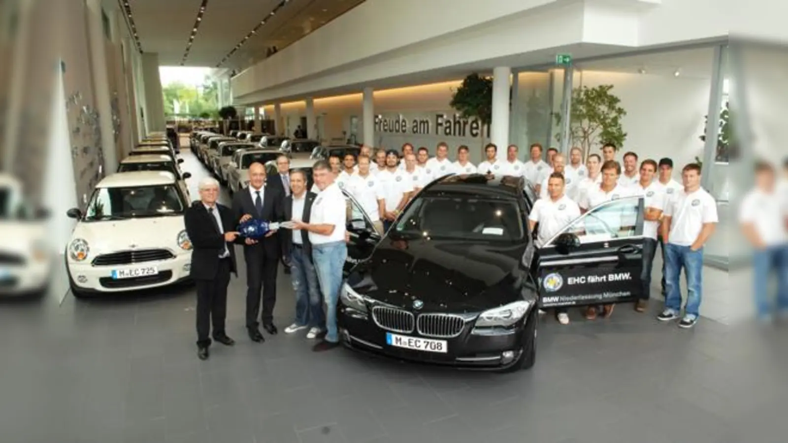 Jürgen Bochanski (EHC), Dirk Kemmer (BMW), Thomas Kriner (EHC) und Pat Cortina (EHC, vorne v. li.)  mit dem gesamten Spielerkader des EHC München.	 (Foto: BMW)