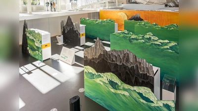 Tosende grüne Wellen, schwarzgraue Gesteinsformationen, orangeleuchtender Himmel: Blick auf die Sonderausstellung „Simpel, komplex, lebendig” in der Eingangshalle des Deutschen Museums, die sich in urzeitlicher Kulisse mit der Entstehung des Lebens auf unserem Planeten befasst. (Foto: Deutsches Museum/ Reinhard Krause und Hubert Czech)