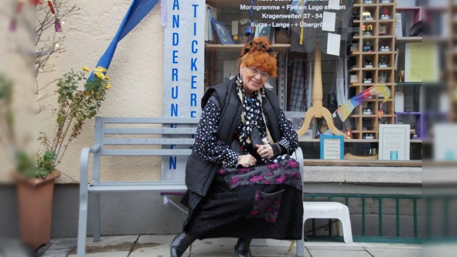 Hannelore Scherer auf der Bank vor ihrem Laden. Ihr Markenzeichen ist ihr Maßband, das sie immer um den Hals hängen hat. (Foto: bb)