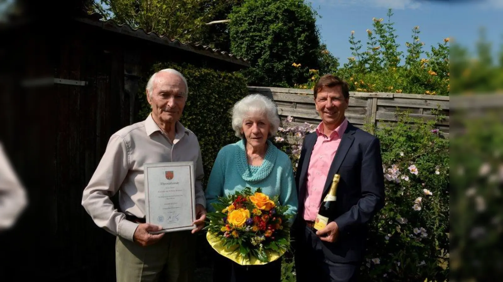 Feiern ihre Eiserne Hochzeit: Willi und Centa Baudrexl. Im Namen der Stadt gratulierte der zweite Bürgermeister Horst Martin (r.) und brachte Blumen, Sekt sowie ein Präsent des Ministerpräsidenten mit. (Foto: mka)
