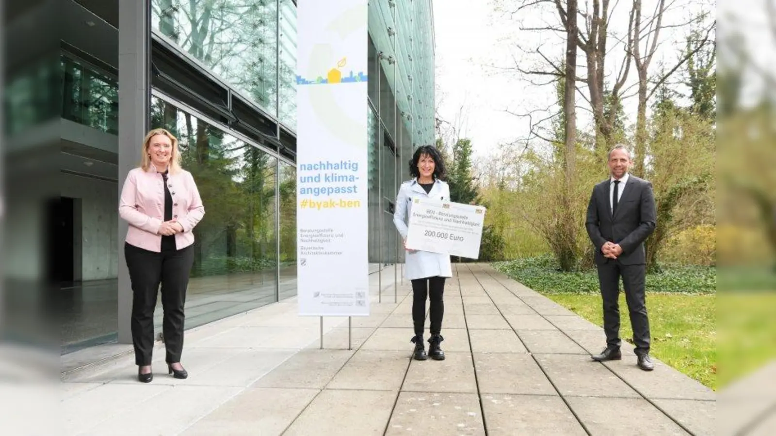 Bauministerin Kerstin Schreyer (links) und Umweltminister Thorsten Glauber überreichten der Präsidentin der Bayerischen Architektenkammer, Christine Degenhart, den Förderscheck. (Foto: ByAK, Tobias Hase)