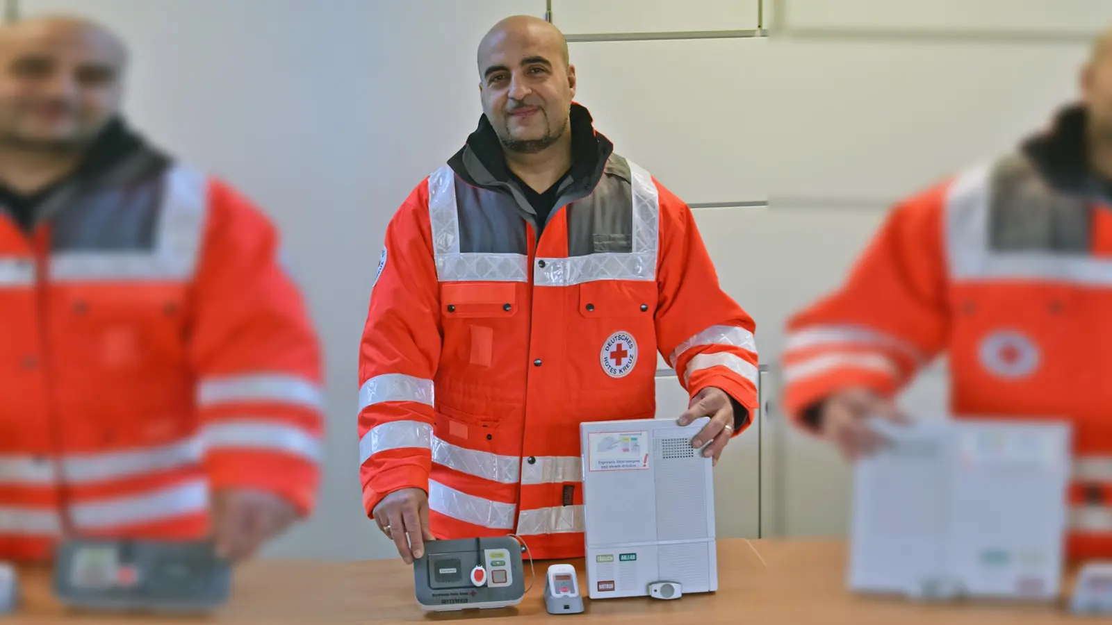 Bereichsleiter Soziale Dienste Tarek El-Katat zeigt das aktuelle Gerät, den Mobilruf und eines der ersten Geräte (von links). (Foto: Danuta Pfanzelt)