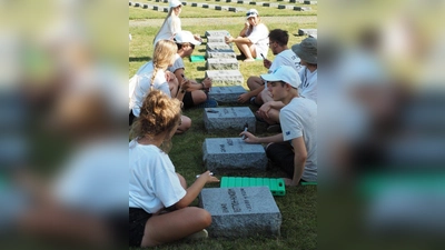Junge Leute pflegen die Gräber der Opfer von Krieg und Gewaltherrschaft auf dem Waldfriedhof. (Foto: Volksbund)