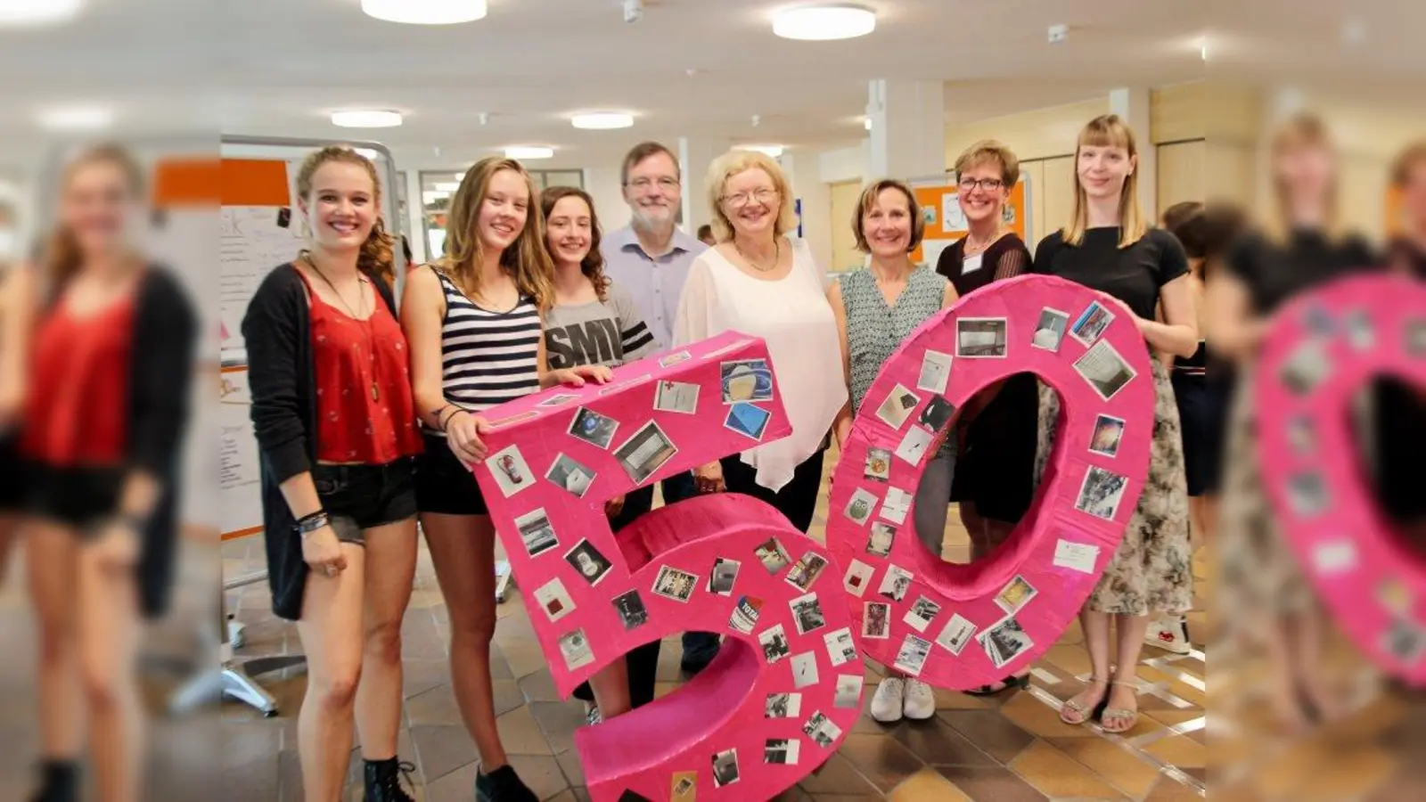 „Schule mit Vorbildcharakter”: Schulleiterin Ingrid Warmbein und Stellvertreter Wolfgang Everlein sowie die Lehrerinnen Cora Dippold, Cornelia Aicher-Leonbacher und Uta Biron vom Schulforum (v.r.) mit den Schulsprecherinnen. Die bunten Jubiläumszahlen entstanden im Kunstunterricht der achten Klassen. (Foto: us)