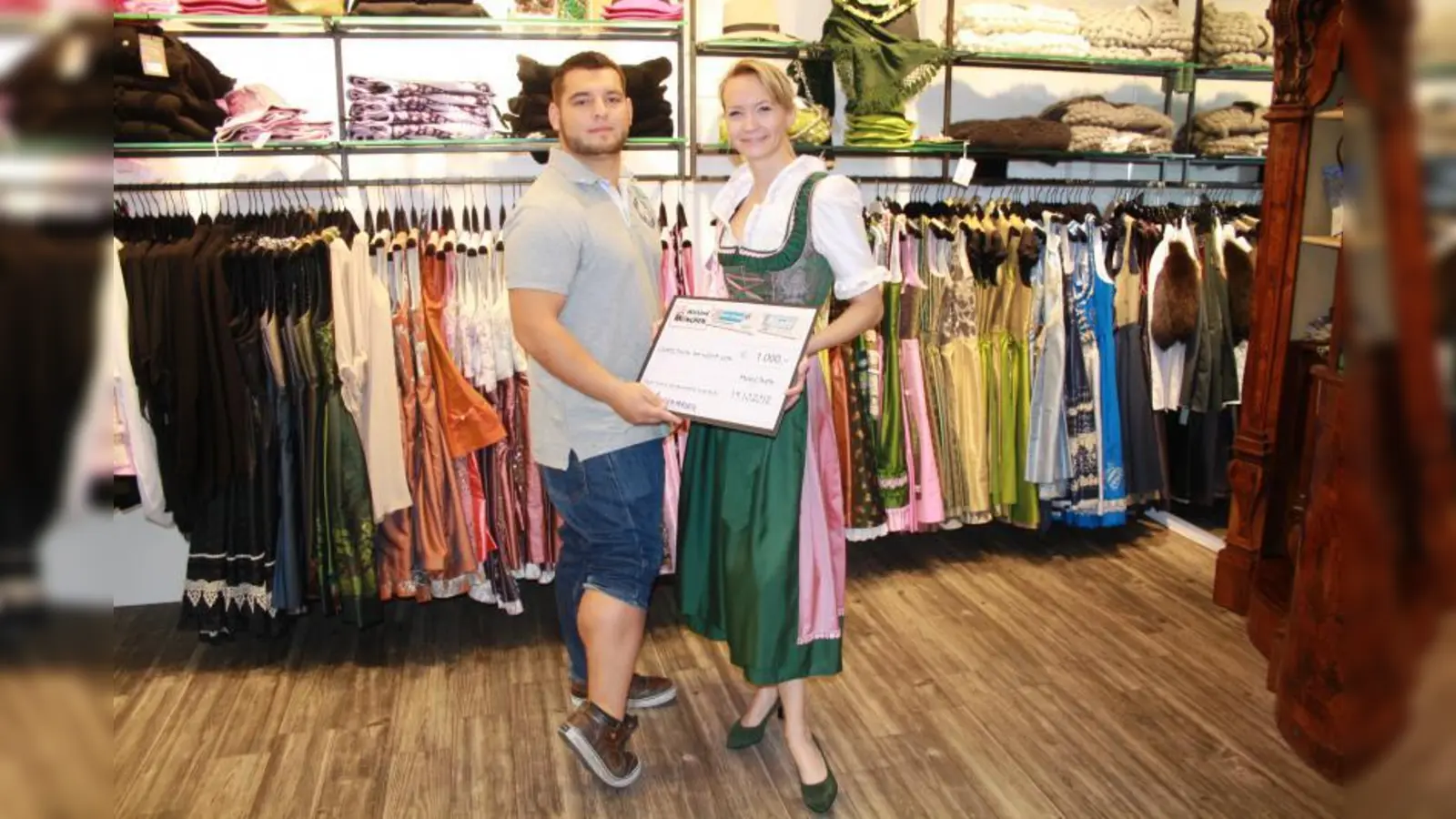 Eileen Krajewski, Mitarbeiterin bei Trachten Angermaier, überreichte Efe Kara alias „Mister Wadl” einen Gutschein im Wert von 1.000 Euro für die strammten Wadln Münchens. (Foto: E.S.)