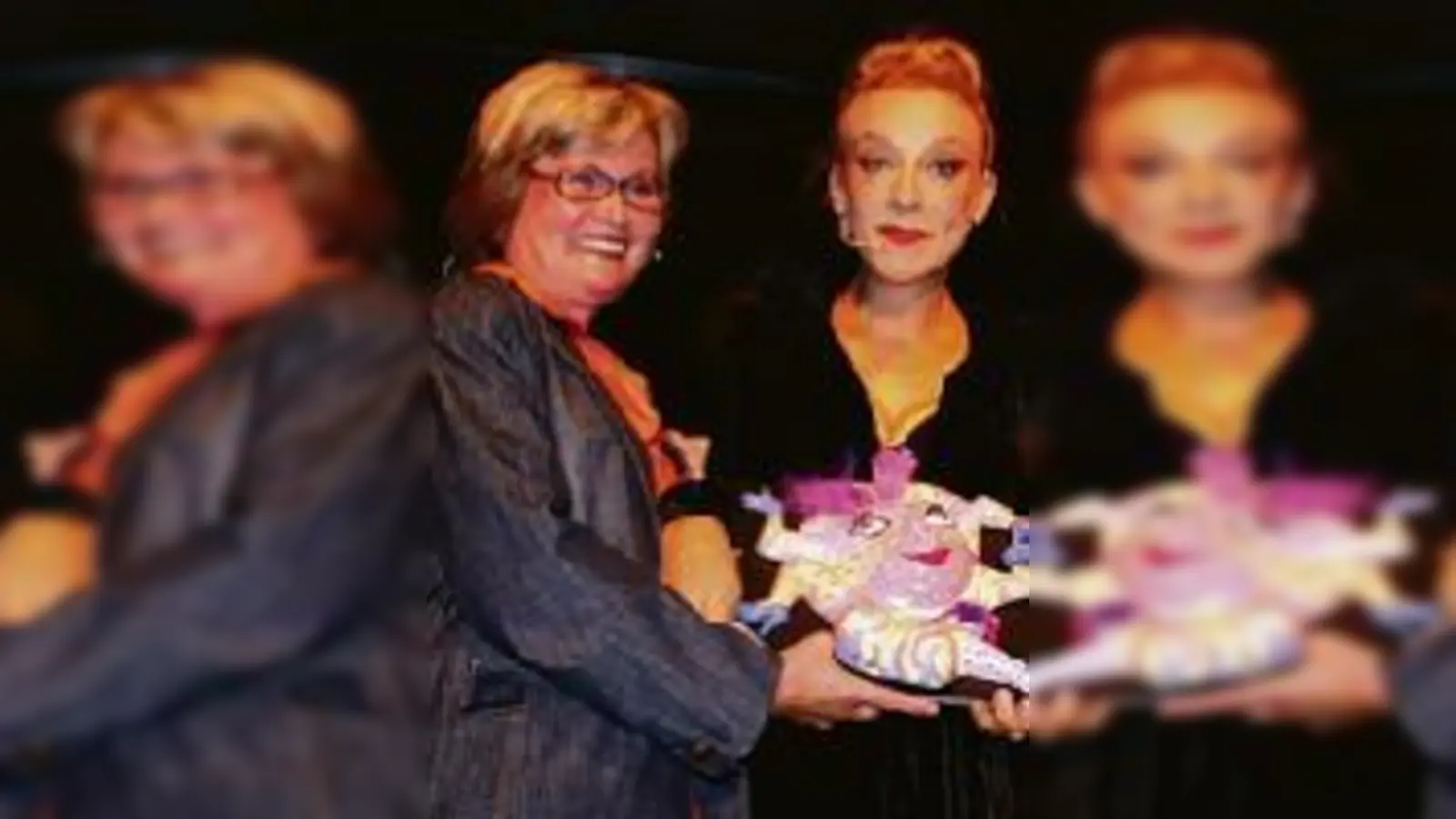 Nach dem Pokerface: Künstlerin Birgit Niemes (l.) und Vhs-Leiter Herbert Becke überreichen Sissi Perlinger die 15. Kleinkunstmaske.	 (Foto: gf)