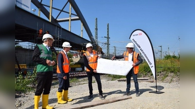 Gesamtprojektleiter Kai Kruschinski (Mmitte) und Jens Reh von der Arbeitsgemeinschaft der Baufirmen (rechts) erklärten Ministerialdirektor Helmut Schütz (Bayerisches Verkehrsministerium, ganz links) und Klaus-Dieter Josel, DB-Konzernbevollmächtigter in Bayern (Zweiter von links), wie die Stabbogenbrücke an ihre finale Stelle geschoben wird. (Foto: DB/Maximilian Endrös)