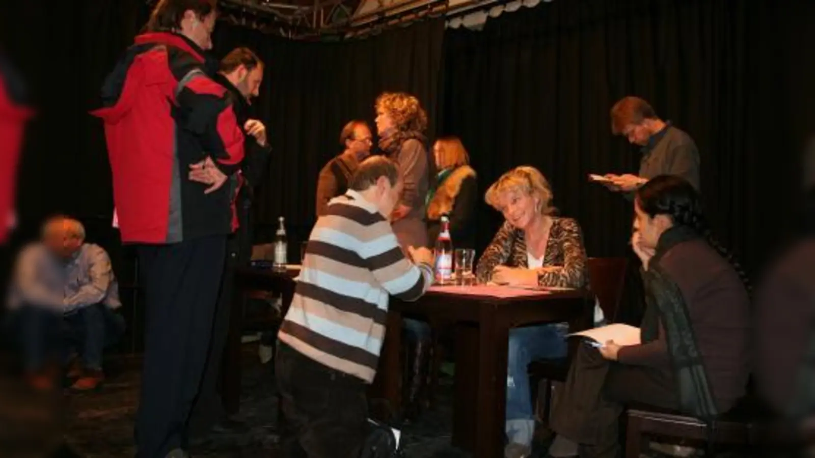 Dicht umringt im „Interim”: die Ansprechpartner des Kulturreferats für die Laimer Stadtteilwoche. Sogar knieend füllte einer, der mitmachen will, seine Anmeldung aus. (Foto: tg)