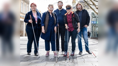 Stefanie Freitag (BBSB), Sofia Langmeier (Die Grünen), Stefan Jagl (Die Linke), Barbara Likus (SPD) und Roland Hefter (SPD) testen in der Fußgängerzone – ausgestattet mit Langstöcken und Simulationsbrillen – den sogenannten Leitstreifen, eine Regenrinne aus aus Pflastersteinen. (F.: Kerstin Keysers)