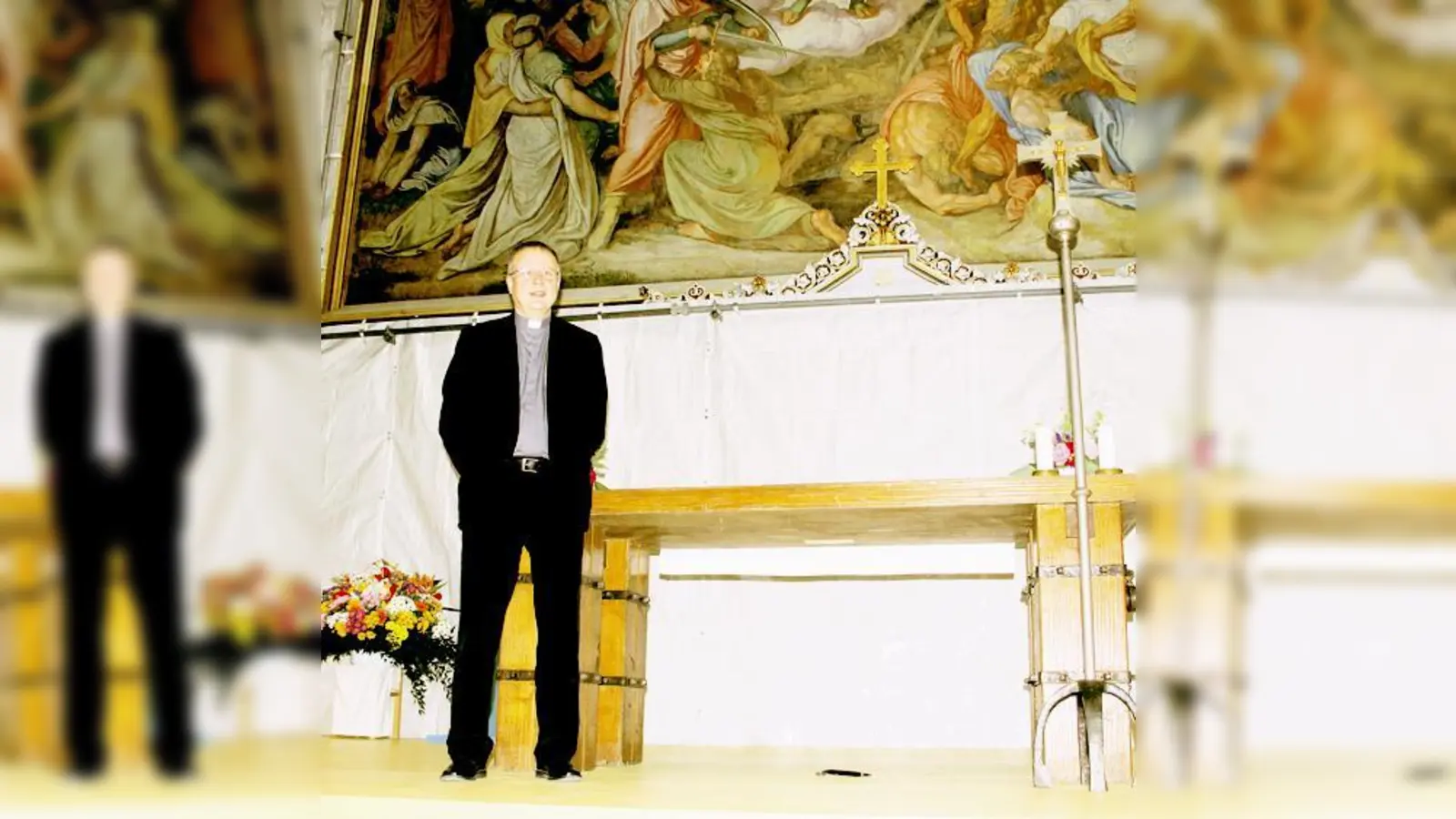 Findig hat Pfarrer Ulrich Babinsky den behelfsmäßigen Altar nach vorne verlegt: Die Folie mit dem Gemäldefoto verdeckt die dahinterliegenden Baugerüste. 	 (F.: ko)