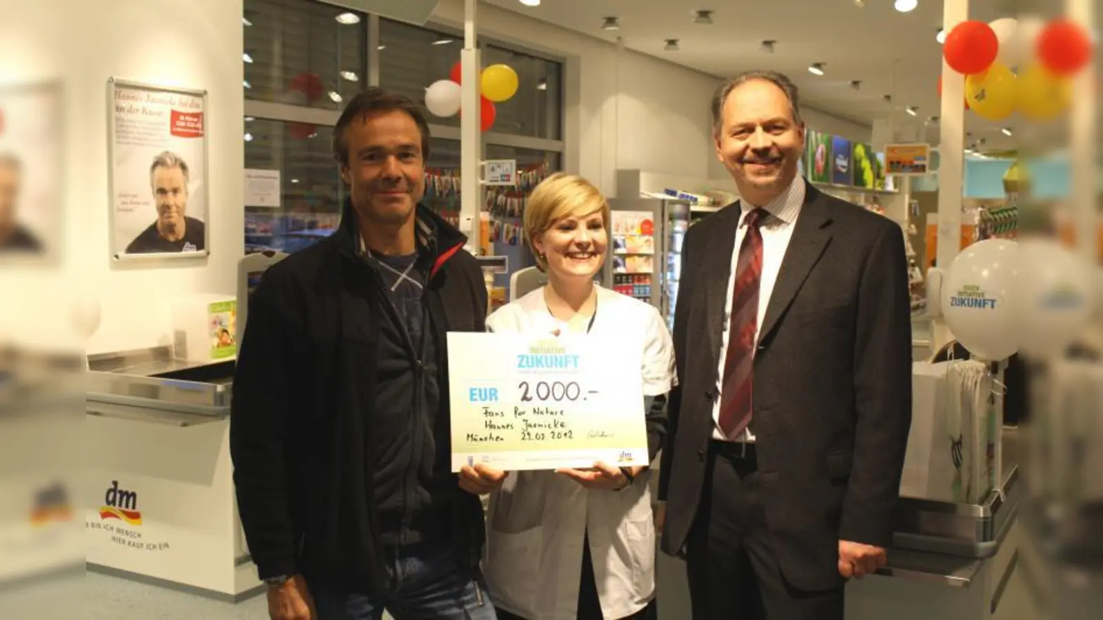 Bernd Kornmayer (re.), dm-Gebietsverantwortlicher, und die Leiterin der dm-Filiale am Frankfurter Ring, Sabrina Stieglmeier, übergeben den Scheck in Höhe von 2000 Euro an Schauspieler und dm-Nachhaltigkeitsbotschafter Hannes Jaenicke. (Foto: sb)