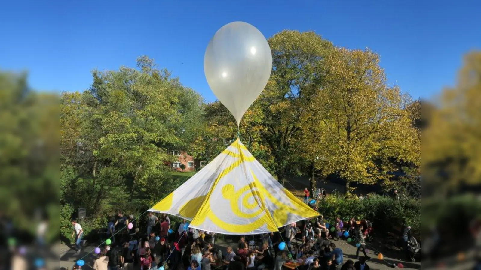 Der Parkplatz des Alten- und Servicezentrums Laim verwandelte sich für das Laimer Herbstfest zum Festplatz. Die Gestaltung des luftigen Festdachs mit weißem Fesselballon stammt von der Künstlerin Sophie Johanna Kaiser. (Foto: Trixi Klein/ Initiativgruppe Zschokkestraße)