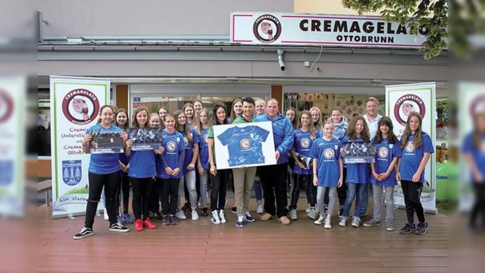 Die Fußballerinnen mit Trainer Benedikt Spötzl (3.v.r.) präsentieren ihre neuen Trikots. Als Hauptsponsor gewann der Sponsoring-Verantwortliche des Vereins, Patrick Ahlbrecht, Valentina und Cristian Visentin (Mitte) von der Eisdiele »Cremagelato«.  (F: priv)