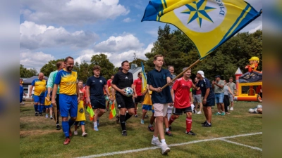 Mit wehender Vereinsfahne auf den Platz: Die DJK Pasing Allstars und der FC Sternstunden beim gemeinsamen Einlauf zum Benefizspiel anlässlich des 70-jährigen Jubiläums der DJK Pasing. (Foto: Christian Riedel/fotografie-riedel.net)
