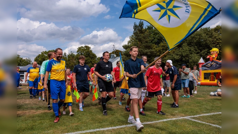 Mit wehender Vereinsfahne auf den Platz: Die DJK Pasing Allstars und der FC Sternstunden beim gemeinsamen Einlauf zum Benefizspiel anlässlich des 70-jährigen Jubiläums der DJK Pasing. (Foto: Christian Riedel/fotografie-riedel.net)