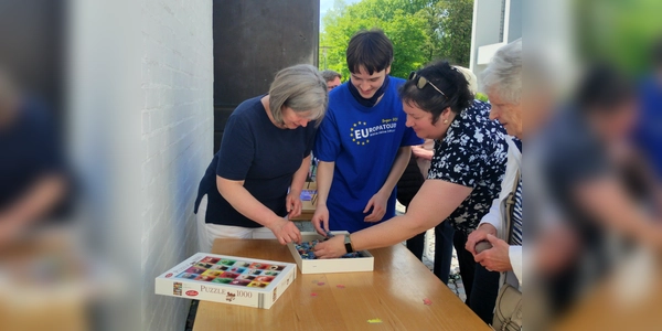 Pfarrgemeinderatsvorsitzende Dr. Andrea Hermann (1. v. l.) und Bücherei-Ehrenamtlicher Jakob Sunderer (2. v l.) legen die ersten Puzzleteile und eröffnen damit die neue Puzzle-Aktion in der Bücherei St. Martin in Germering. (Foto: St. Martin)