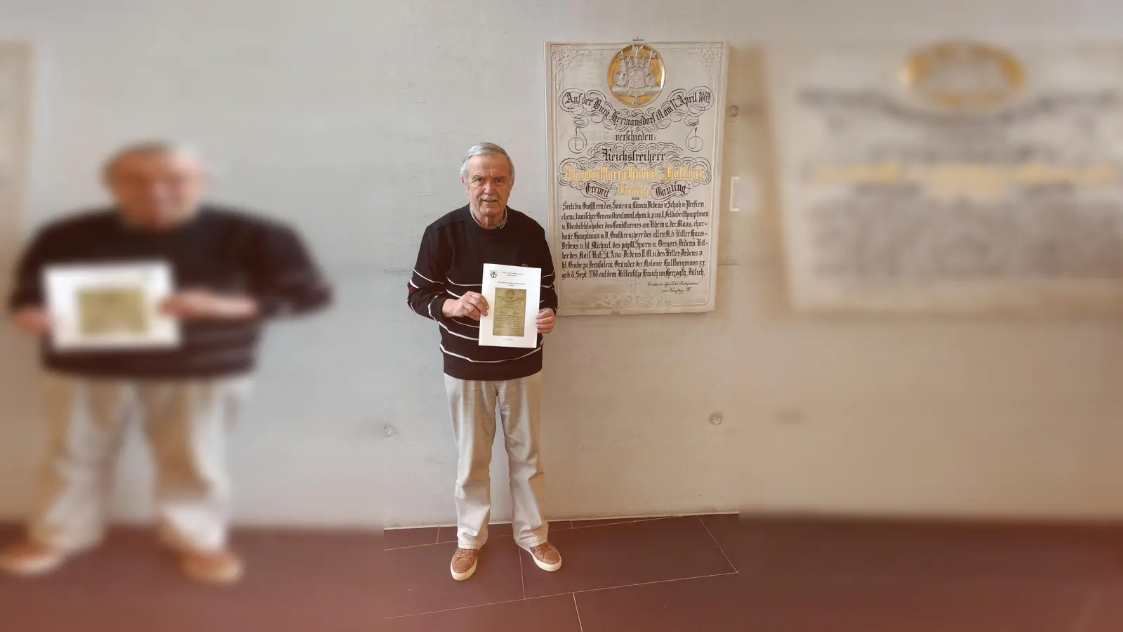 Karl-Heinz Zenker mit dem neuen Sammelblattband vor der Gedenkplatte des Freiherrn von Hallberg, die im Foyer des Rathauses hängt. (Foto: privat)