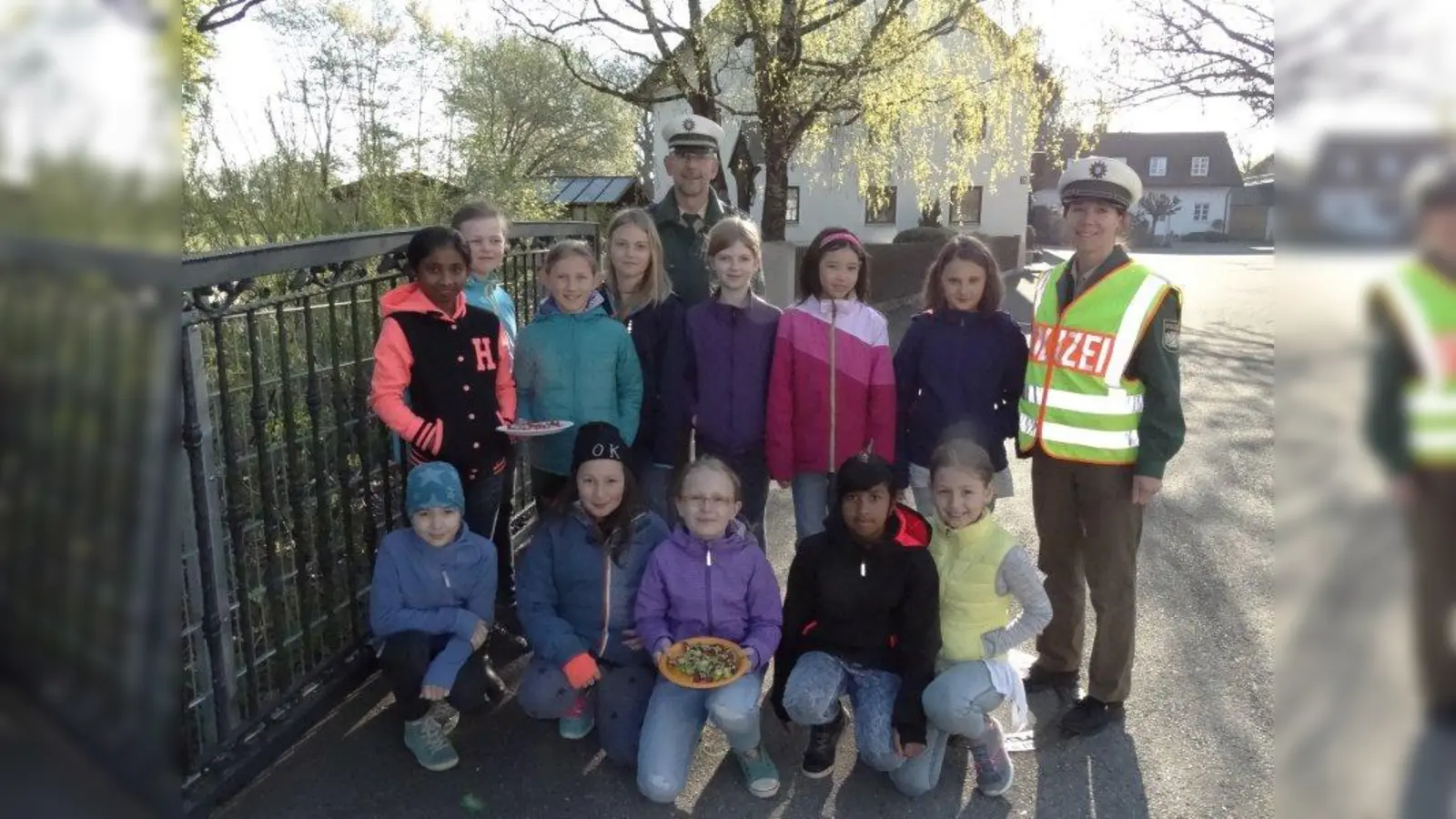 Michael Reisch von der Verkehrsabteilung des Polizeipräsidiums München und Edith Paproth von der PI 41 bei der gemeinsamen Aktion „Süßes oder Saures” mit den Mädchen der Klasse 4c. (Foto: tab)