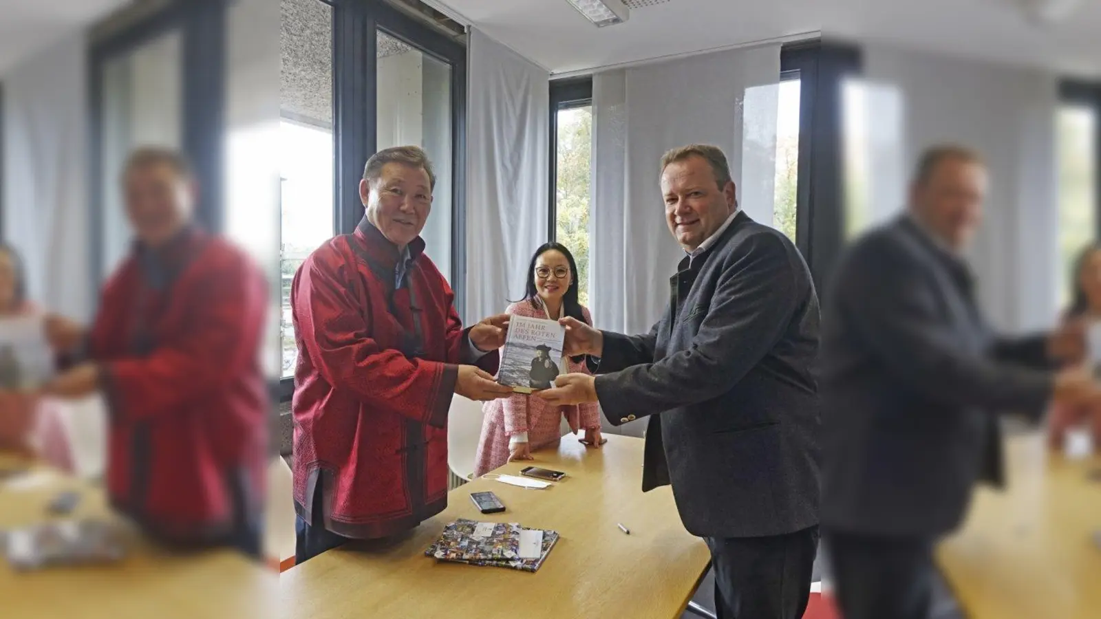 Dendev Terbishdagva (links) überreichte Bürgermeister Peter Köstler eine Ausgabe seines Buches „Im Jahr des roten Affen”. Zustande kam der Austausch durch Ochmaa Göbel (Mitte), die erste Mongolin, die in Deutschand ein Mandat innehat. (Foto: Birgit Doll)