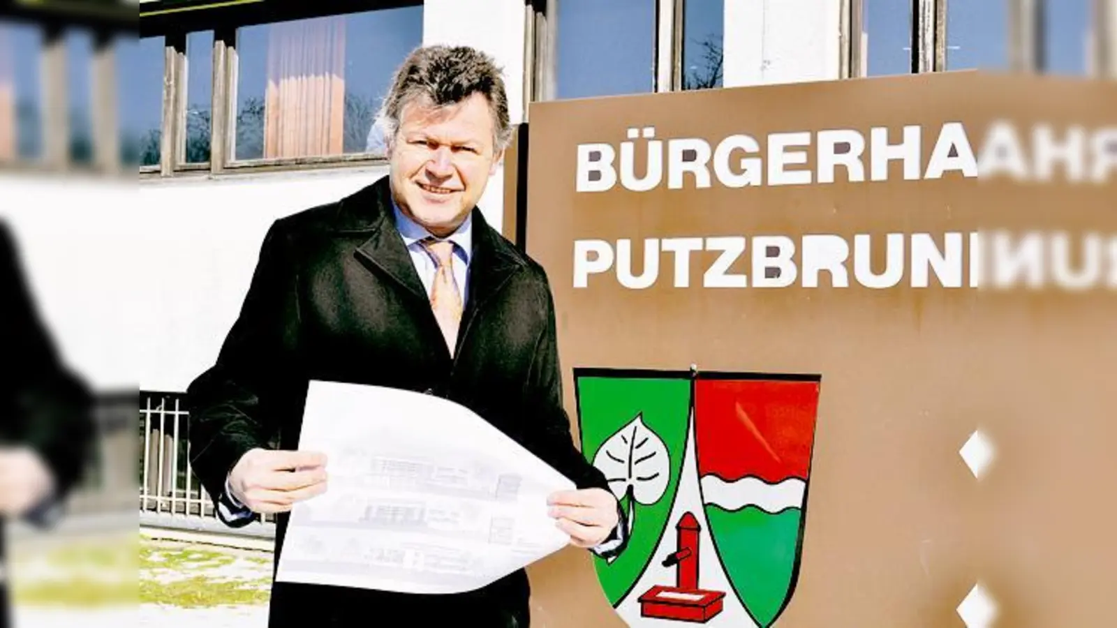 Bürgermeister Edwin Klostermeier mit einer Entwurfszeichnung für die Generalsanierung vor dem Bürgerhaus.	 (Foto: Schwarz-Mehrens)