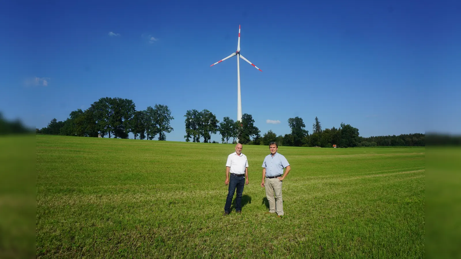 Hans Gröbmayr (l.) von der Energieagentur Ebersberg-München und KUMS-Vorstand Bernhard Wagner im Energiegespräch vor dem Windrad in der Gemeinde Bruck. (Foto: KUMS/bw)