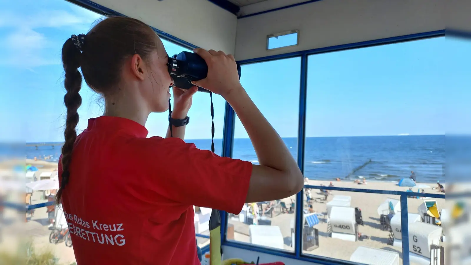 Blick durchs Fernglas: Eine Starnberger Wasserretterin überwacht den Strand vom Wachturm aus. (Foto: BRK)