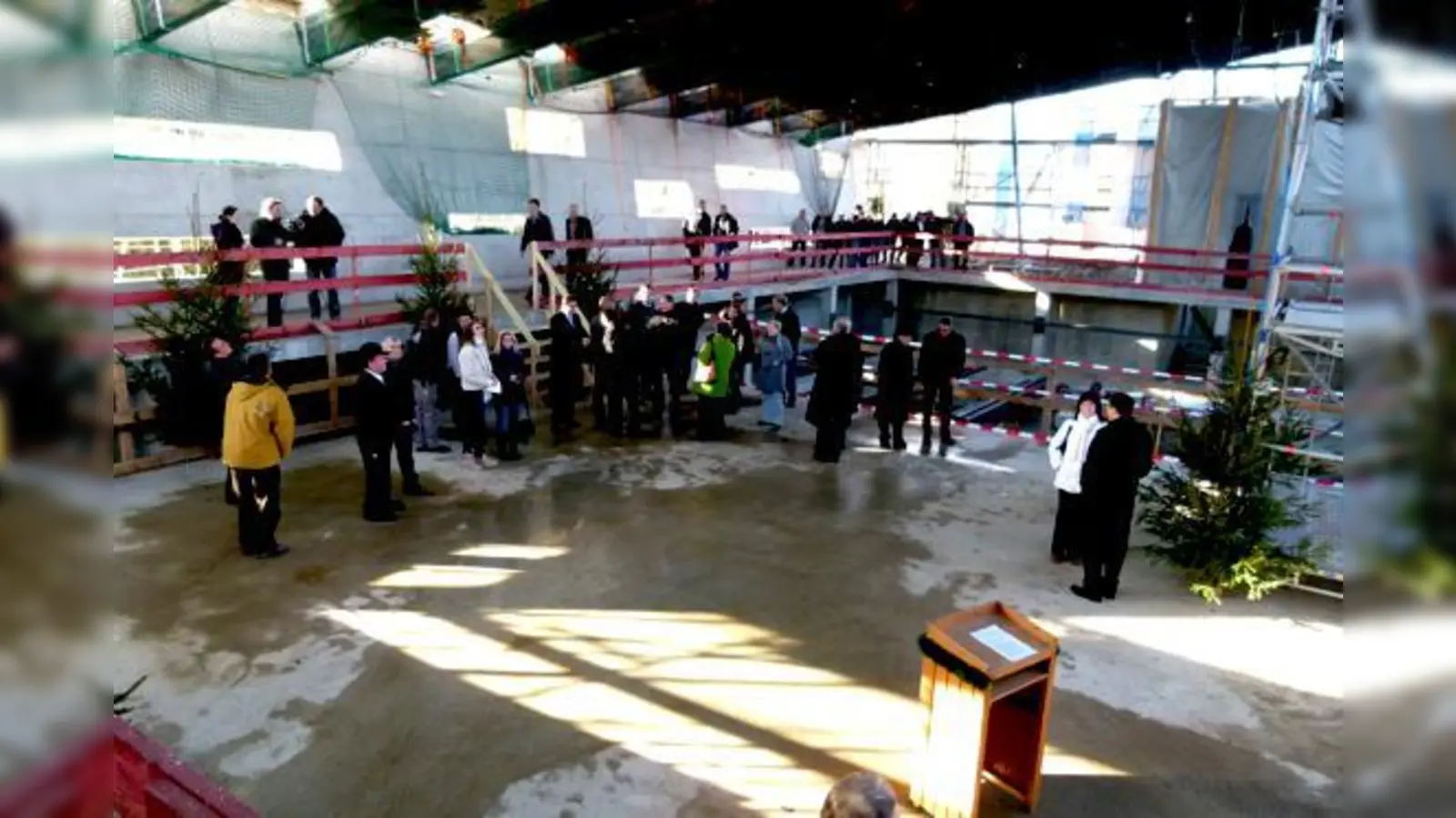 Im seichten Bereich des zukünftigen Lehrschwimmbeckens trafen sich Prominenz, Baubeteiligte und Ehrengäste zur Hebweihfeier. Links die Außenwand, die mit Absicht schräg ist und laut Landrat und Bürgermeister nicht umfallen wird.	 (Foto: bb)