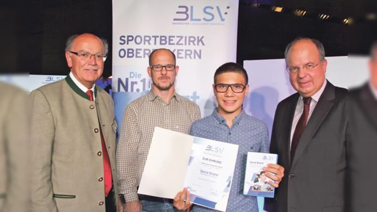 Bezirkstagspräsident Josef Mederer (links) und BLSV-Bezirksvorsitzender Otto Marchner (rechts) gratulierten David Brand und seinem Trainer Aaron Sanders.	 (Foto: alpenPR)