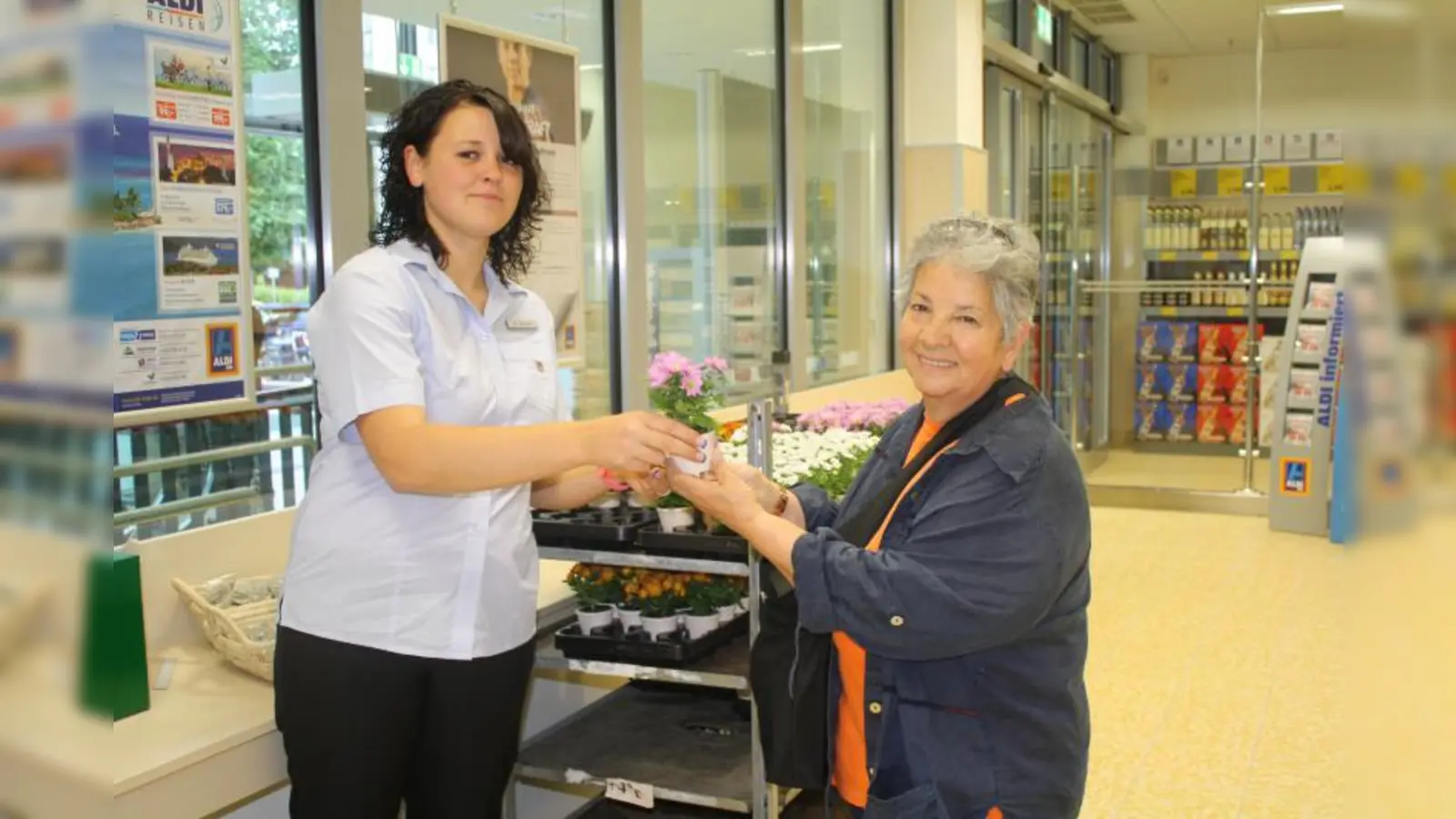 ALDI SÜD-Mitarbeiterin Andrea Abinger überreicht Kundin Mürüvvetu Ozmenzi Blumen als Dankeschön für den Einkauf. (Foto: sb)