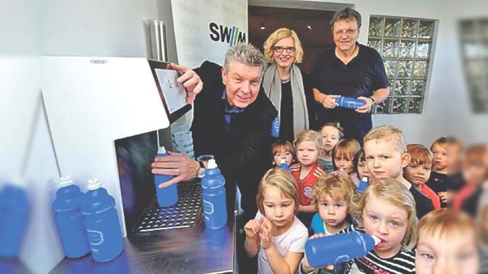 Die jungen Sportler des TSV München Ost probieren mit ihrem 1. Vorsitzenden, Uli Hesse (re.hi.), die M-Wasserbar aus, die ihnen von den SWM in Vertretung durch Erna-Maria Trixl und vom Initiator der Aktion, Dieter Reiter, übergeben wurde. 	 (Foto: SWM)