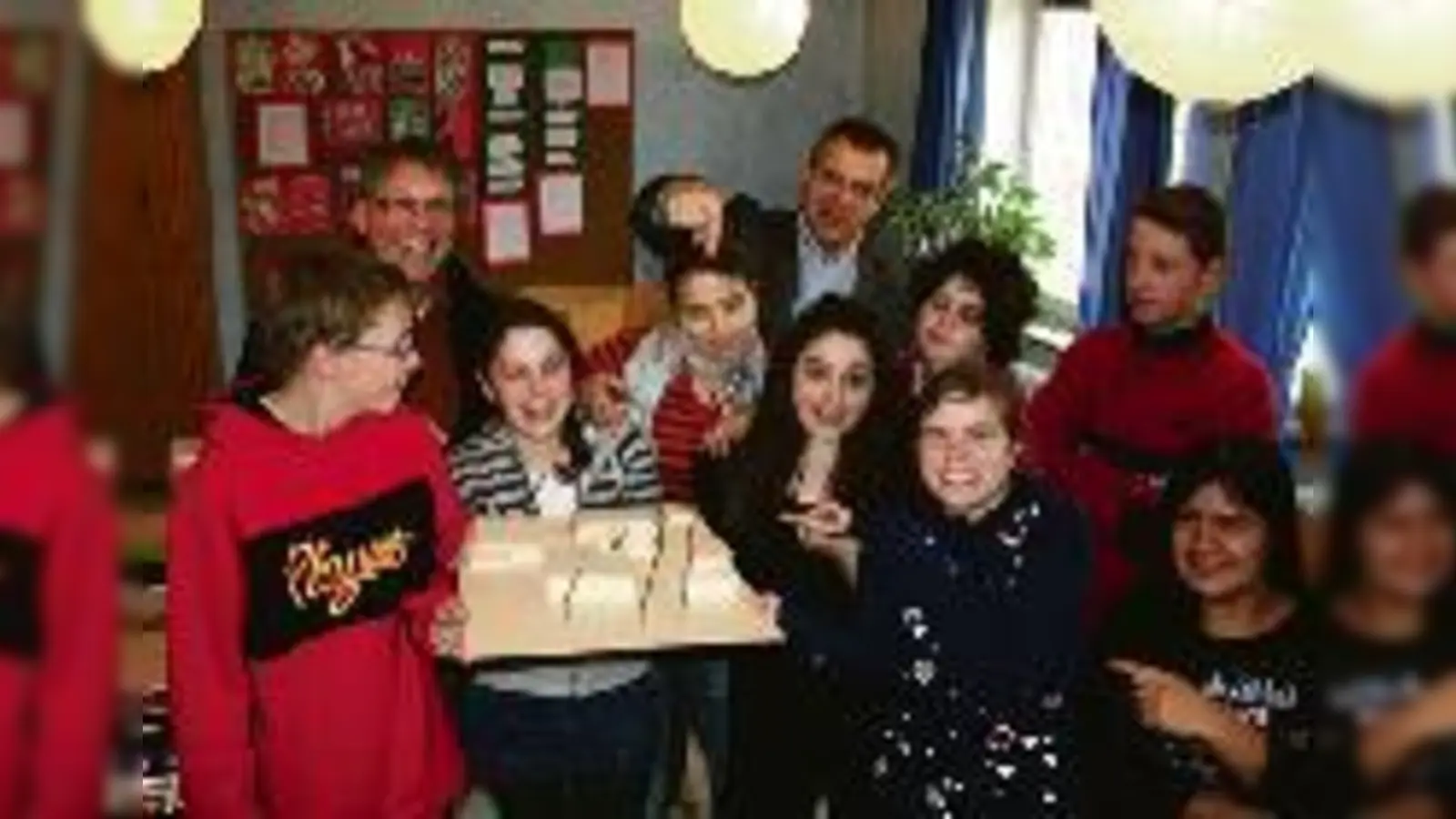 Geschäftsführer G. Müller und J. Lell, Leiter der Parzivâl-Schule (von links), gucken mit Schülerinnen und Schülern, jetzt endlich wieder entspannt in die Zukunft  für die immer noch das Modell des geplanten Neubaus am Ackermannbogen steht.  (F: em)