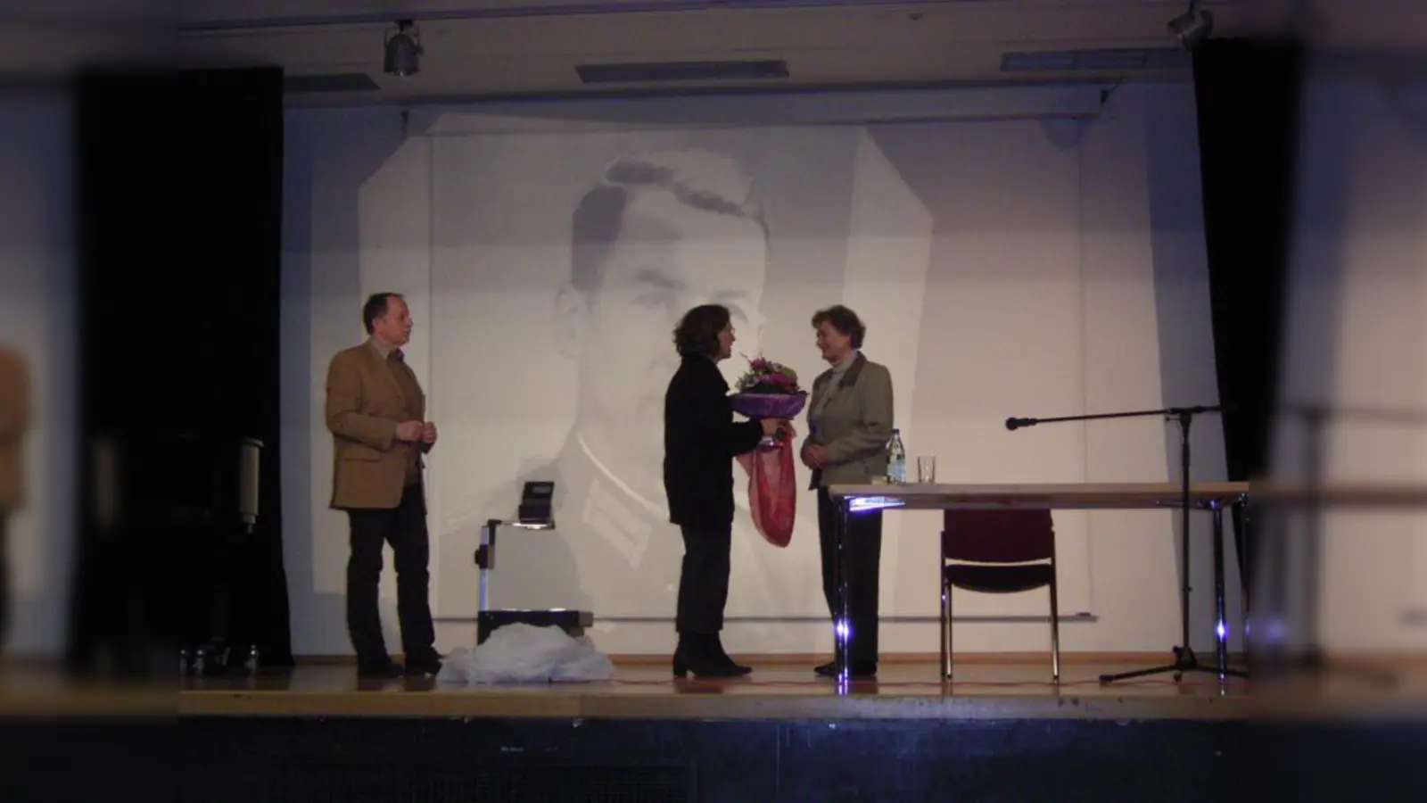 Die Deutschlehrer Karl-Jörgen Simonsen und Rosemarie Mannert bedanken sich bei Jorinde Krejci für die Lesung. Im Hintergrund ist ein Bild ihres Vaters Wilm Hosenfeld abgebildet. (Foto: pi)