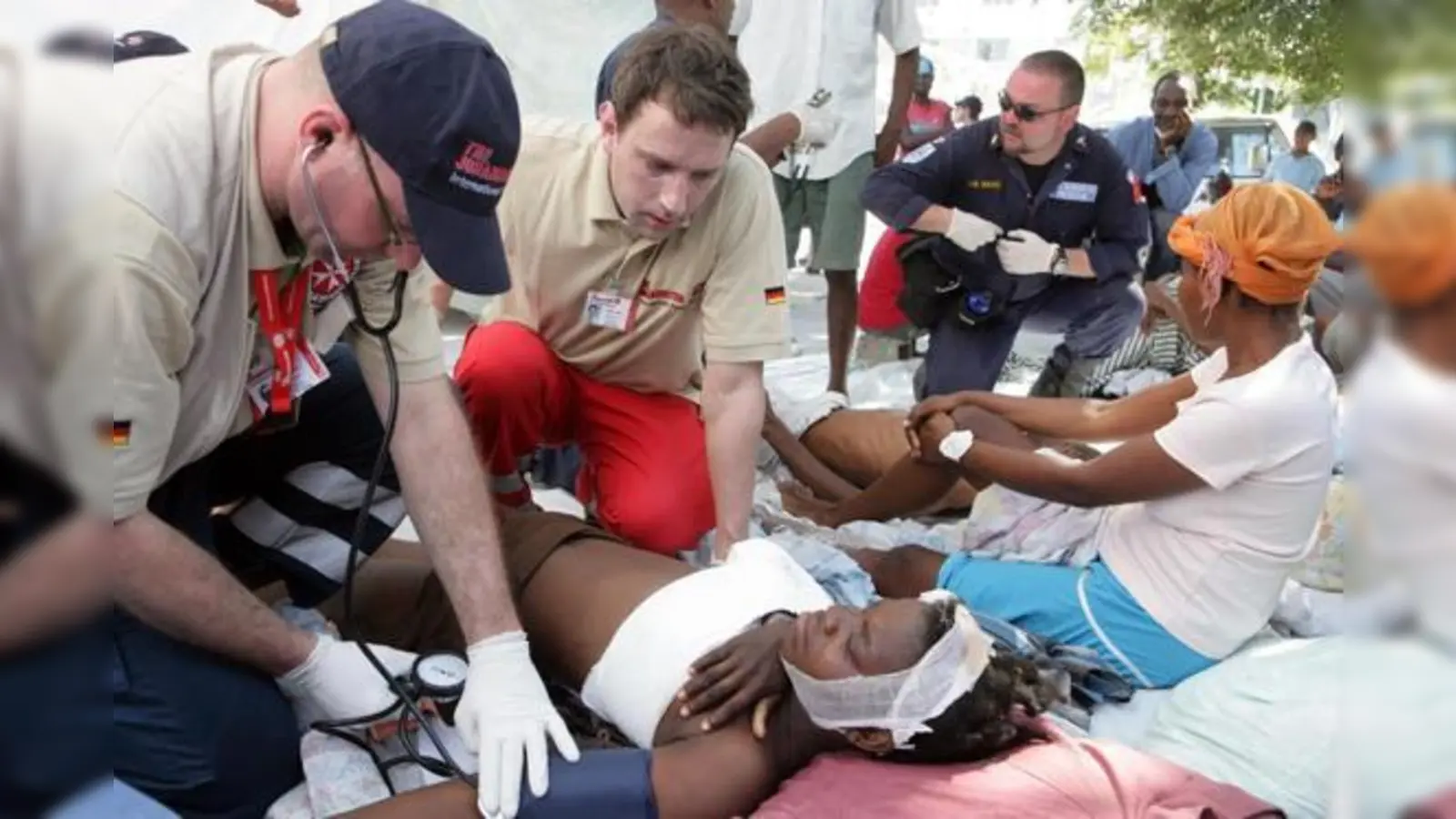 Der Münchner Arzt Dr. Adrian Roth (2.v.li.) untersucht mit seinen Kollegen eine Patientin auf der Straße vor einem überfüllten Krankenhaus in Port-au-Prince.  (Foto: Birgit Betzelt/Johanniter)