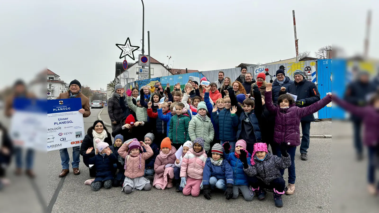 Bürgermeister Hermann Nafziger (l.) hielt zur Vernissage die Sponsorentafel hoch und bedankte sich bei den vielen Kindern, Jugendlichen und erwachsenen Planeggern für ihre Unterstützung am bunten Bauzaun. (Foto: Ulrike Seiffert)