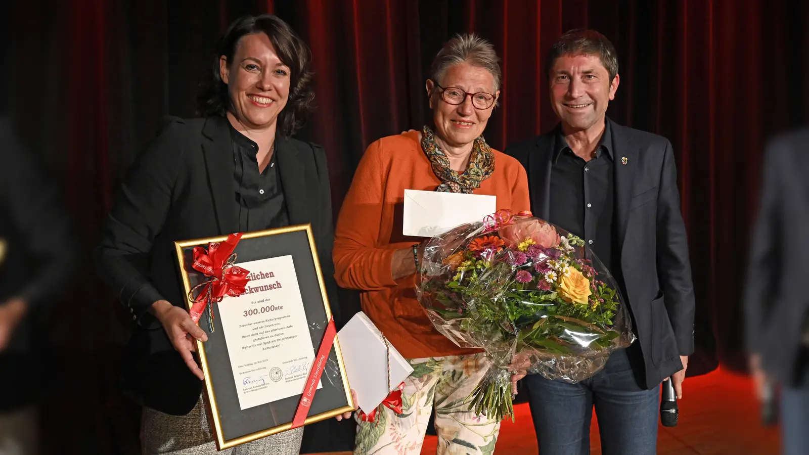 Die 300.000. Besucherin des Unterföhringer Kulturprogramms Doris Rudi (Mitte) mit Kulturamtsleiterin Barbara Schulte-Rief und Bürgermeister Andreas Kemmelmeyer. (Foto: Gemeinde UFG/ulla)