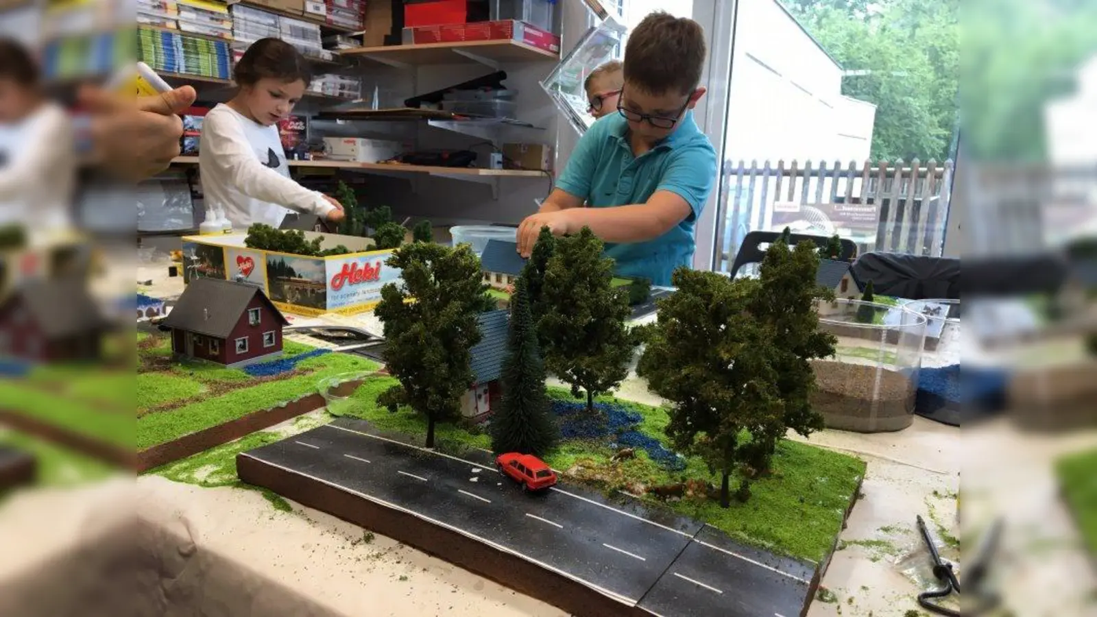 Häuser, Straße, Autos – alles wie in der Realität. Die Kinder gestalten hier ihr eines Landschaftsmodell. (Foto: Modellbahn-Gemeinschaft Germering)