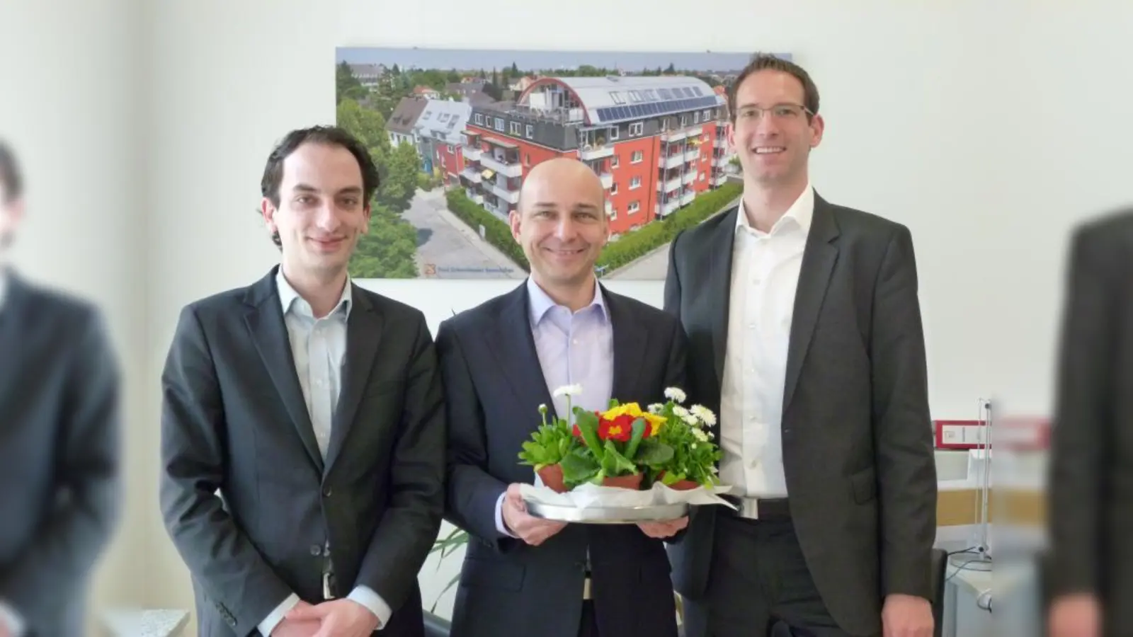 „Uns besuchen hauptsächlich unsere Stammkunden und es ist schön, wenn wir die mit den Blümchen überraschen können“, erklärt Paul Schmidmaier (m.), der gemeinsam mit seinen Kollegen Andreas Wäscher (r.) und Daniel Arnone (l.) die Kundschaft bei Paul Schmidmaier Immobilien GmbH mit Primeltöpfchen empfängt. (Foto: BK)