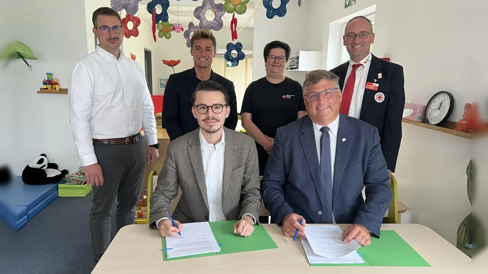 Dennis Behrendt und Stefan Löwl unterzeichnen den Vertrag. Im Hintergrund: Dominik Ulbrich, Michael Schäfer,Larissa Friedl und Bernhard Seidenath. (Foto: BRK Kreisverband Dachau)
